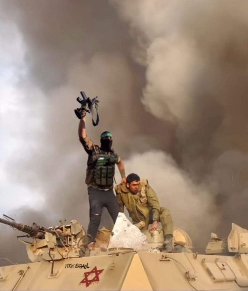 Pejuang Hamas di atas tank Israel sambil memegang prajurit Israel