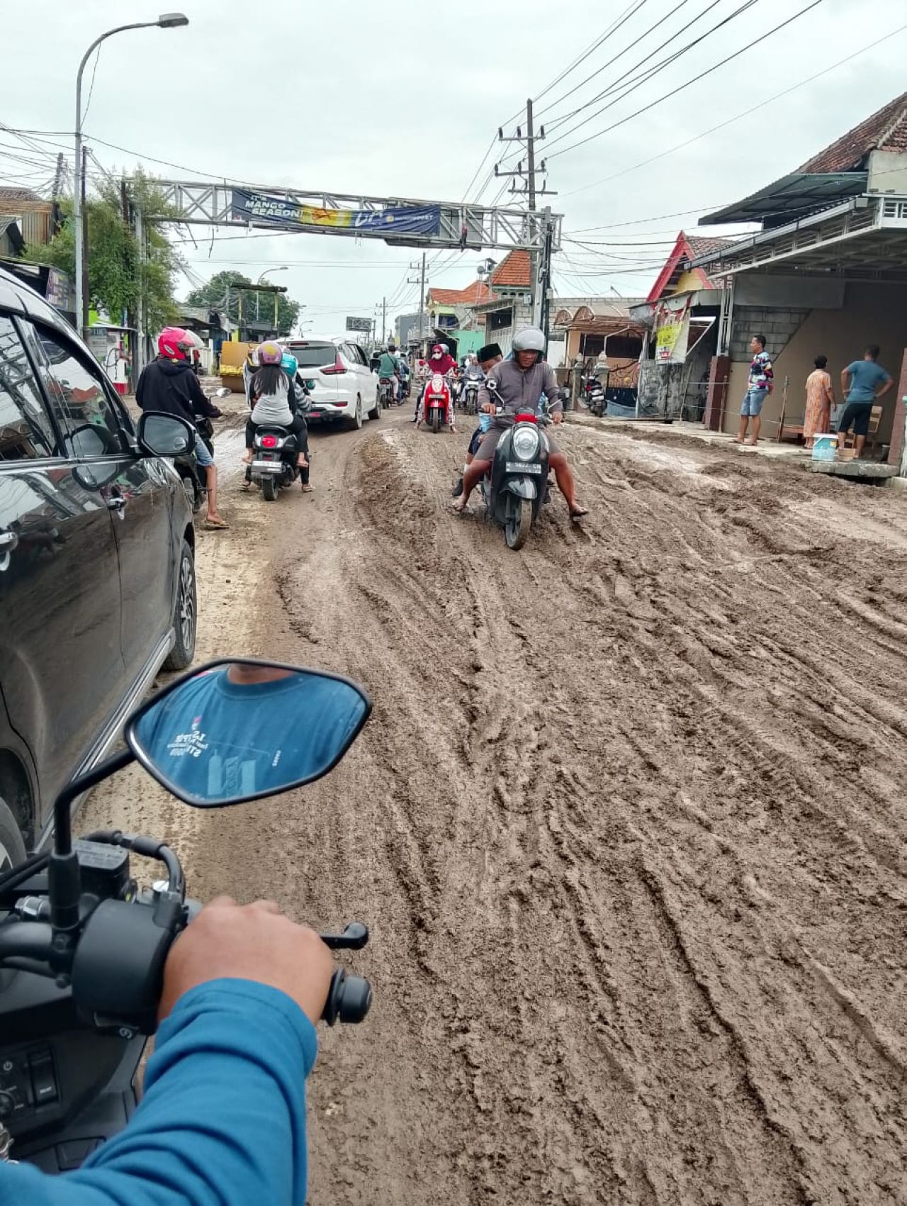 Pemotor kesulitan melintasi jalan yang tertutup lumpur