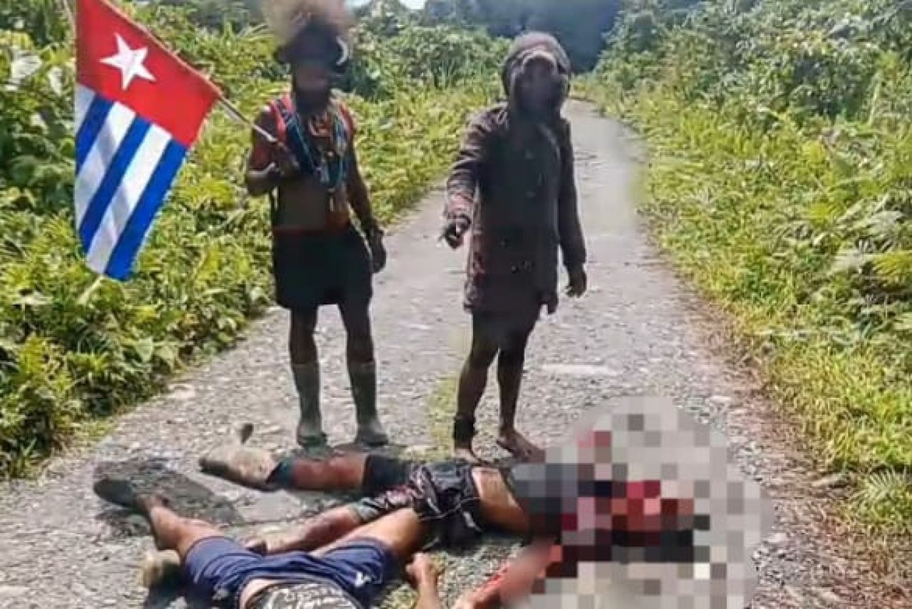 Pasukan OPM berdiri di samping jasad yang dibunuhnya