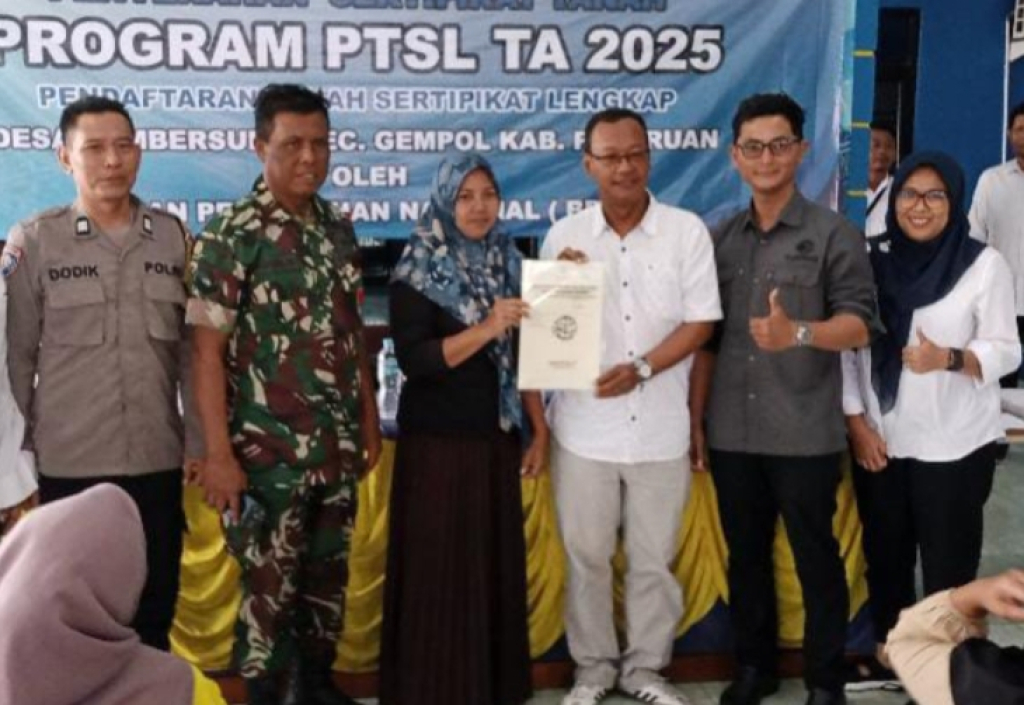 Kepala Desa Sumbersuko (kemeja putih) saat menyerahkan sertifikat ke warga