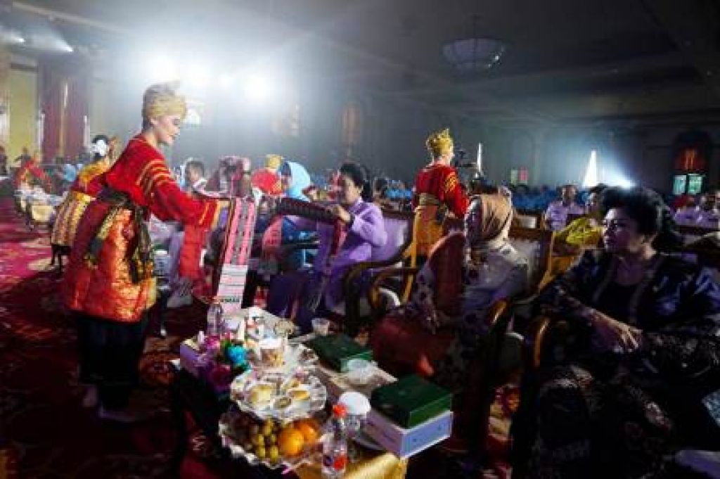 Ketum Dharma Pertiwi menerima kain songket dari salah satu penari 